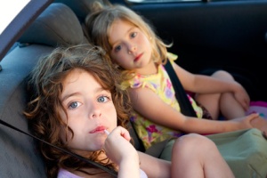 little girls inside car eating candy stick
